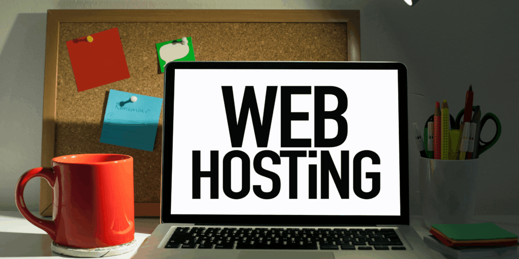 Portátil con el rótulo de alojamiento web en pantalla junto a una taza roja y notas