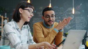 Two colleagues collaborating on a project at a laptop.