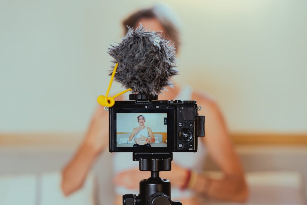 Cámara sobre trípode con micrófono graba a una persona durante la sesión de un videoblog.