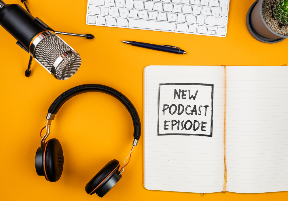 Micrófono, auriculares y un cuaderno con la nota de nuevo episodio sobre fondo amarillo