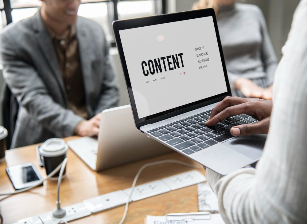Equipo reunido alrededor de un portátil que muestra la palabra content en pantalla