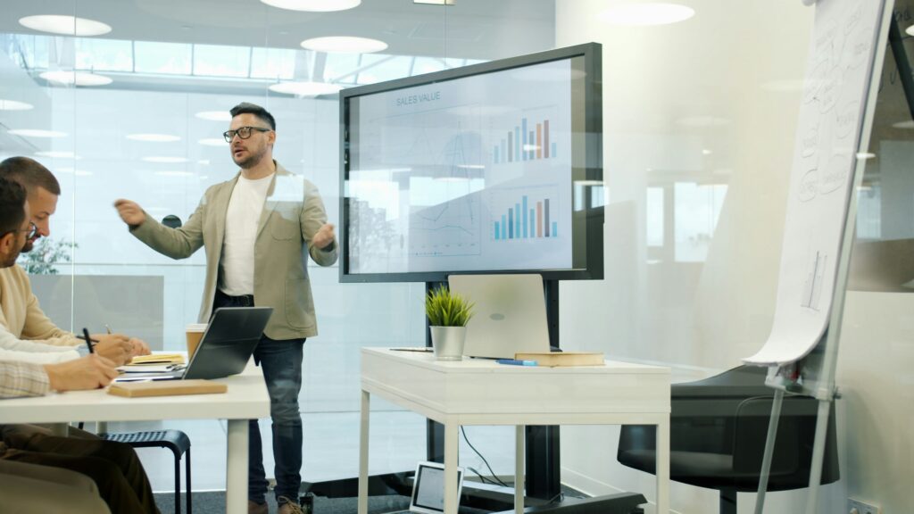 Man presenting data on a large screen to colleagues.