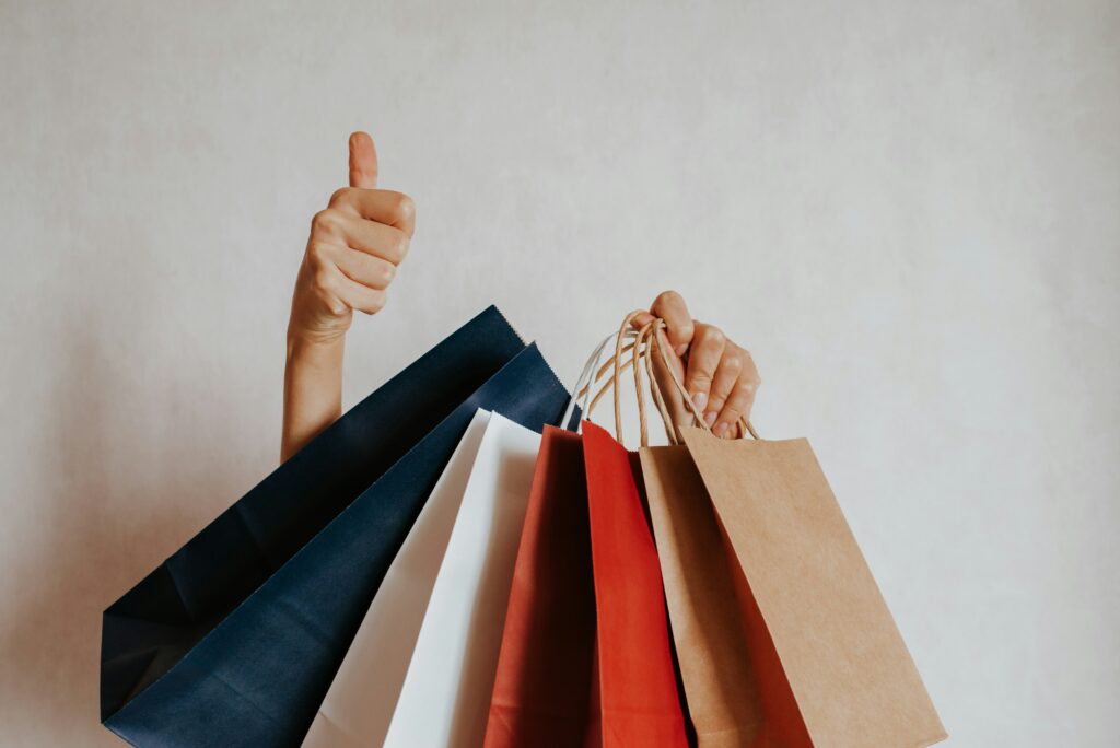 Person holding shopping bags with a thumbs up