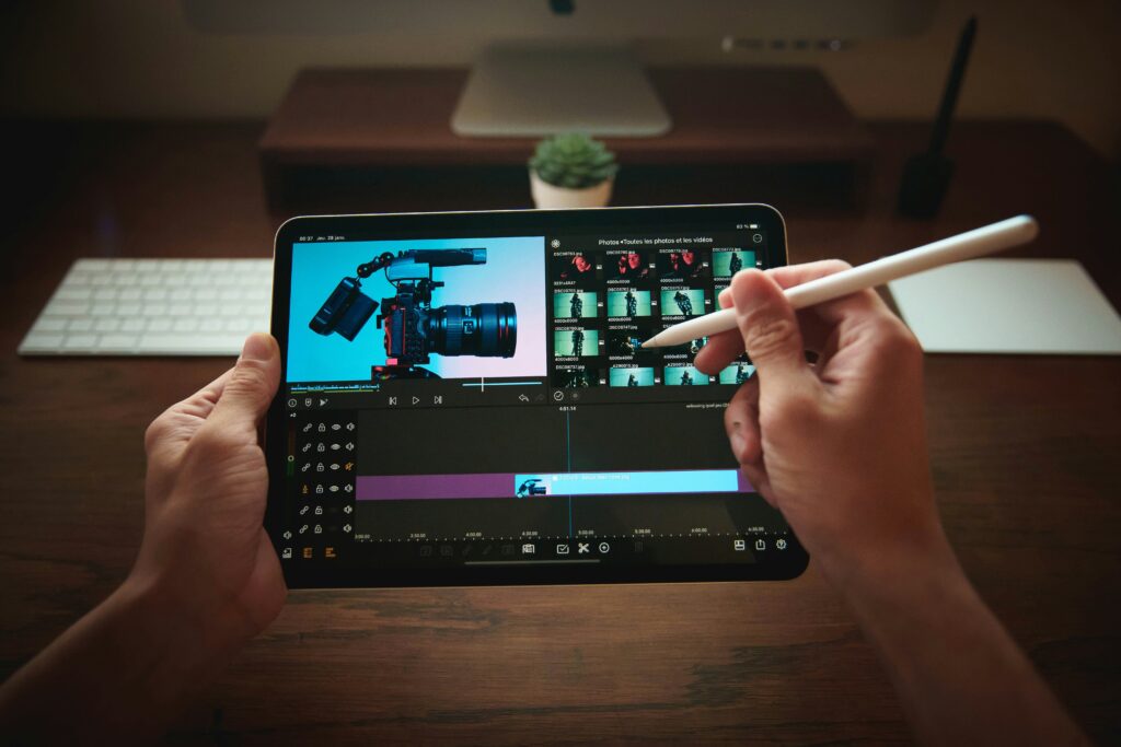 Manos editan una línea de tiempo de video en una tableta con lápiz óptico sobre un escritorio.