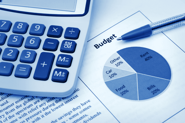 Calculadora y bolígrafo junto a un gráfico circular que reparte un presupuesto por partidas