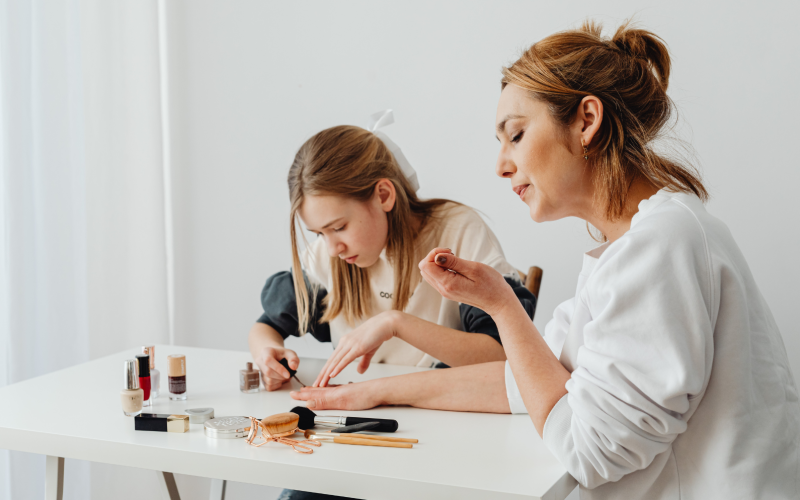 Dos mujeres prueban productos de belleza sobre una mesa blanca con muestras de maquillaje
