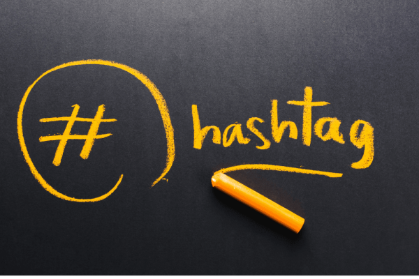 La palabra hashtag escrita con tiza amarilla en una pizarra junto al símbolo de almohadilla